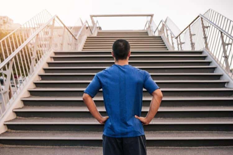 Determined athletic man stands at the bottom of a steep staircase