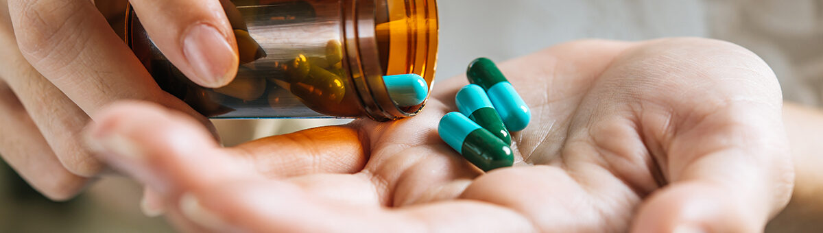 Woman's hand pours the medicine pills out of the bottle