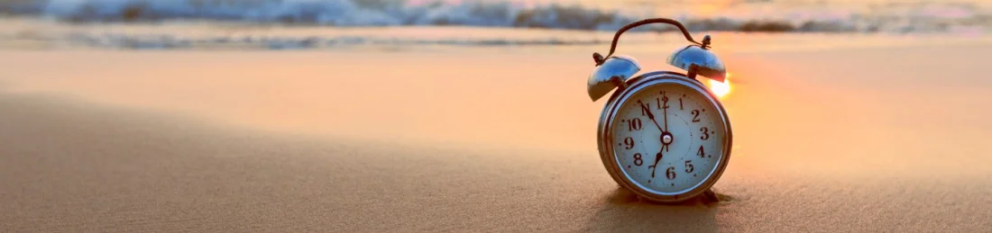 Alarm clock on the beach during sunset