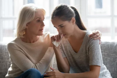 a young woman being comforted by another woman