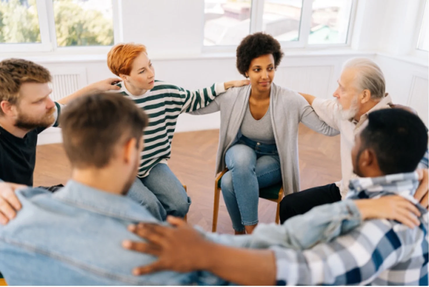 Members of an addiction support group have arms around each other