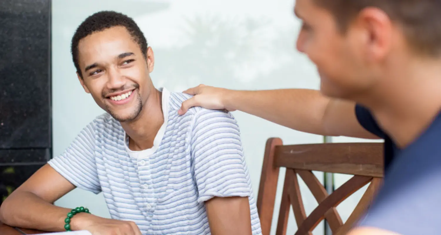 Friend puts reassuring hand on other friend’s shoulder