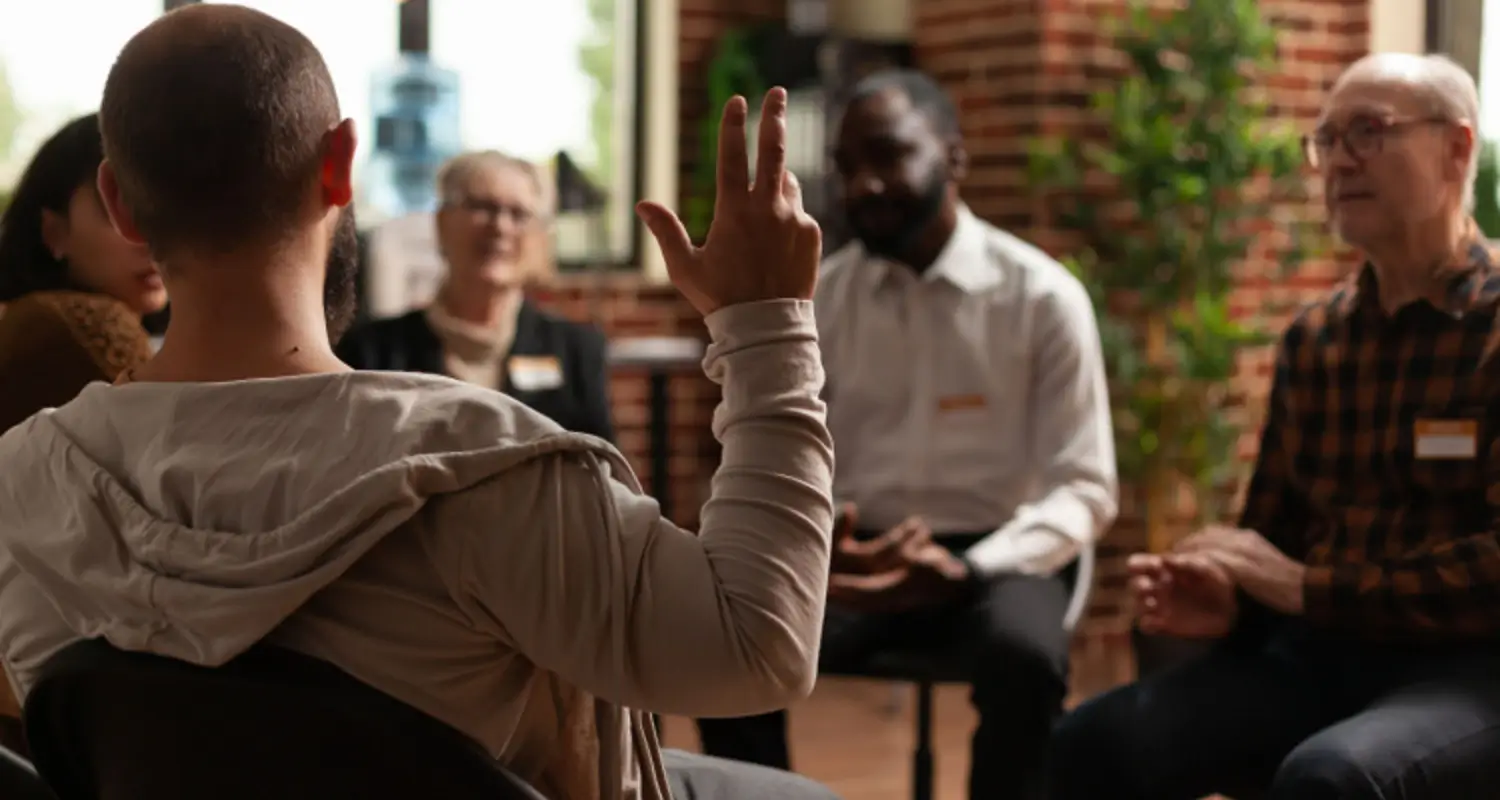 Man in heroin addiction support group raises his hand to speak