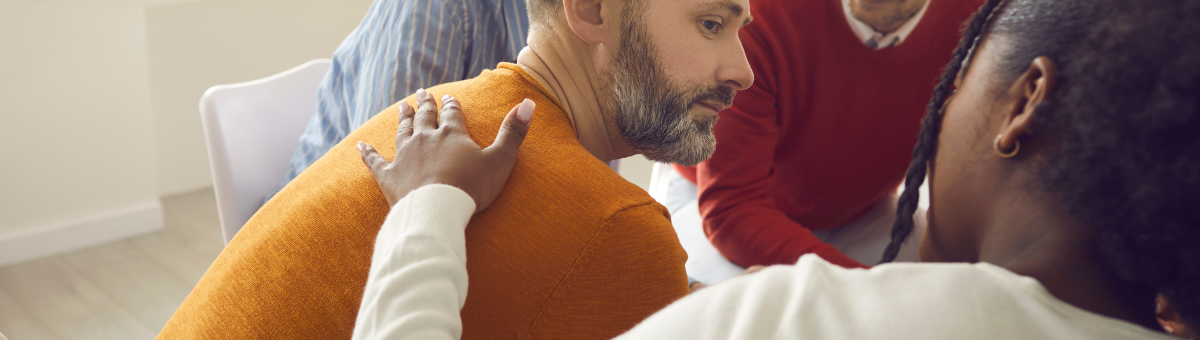 Main in an orange shirt being consoled in therapy